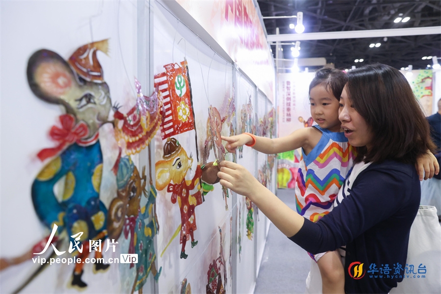 家长与孩子在首届中国（北京）动画周上观看展出的皮影。