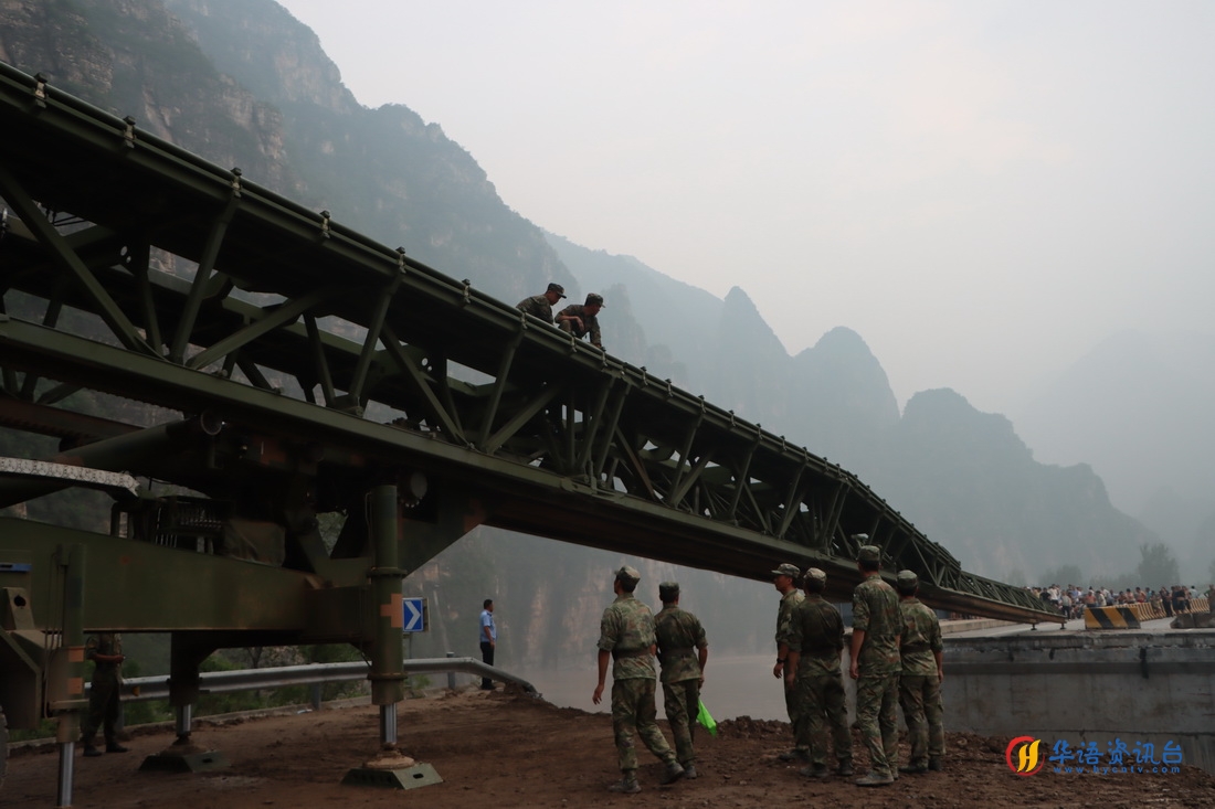 8月3日，中部战区陆军第82集团军某旅在北京市房山区涞宝路四渡桥断桥处架设桥梁，官兵们在推送桥体。新华社发（张康 摄）