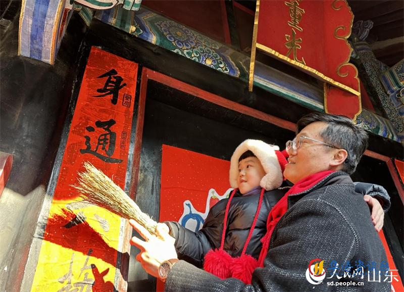 春节前,孔子后裔在孔府重光门前贴春联。 人民网 乔姝摄